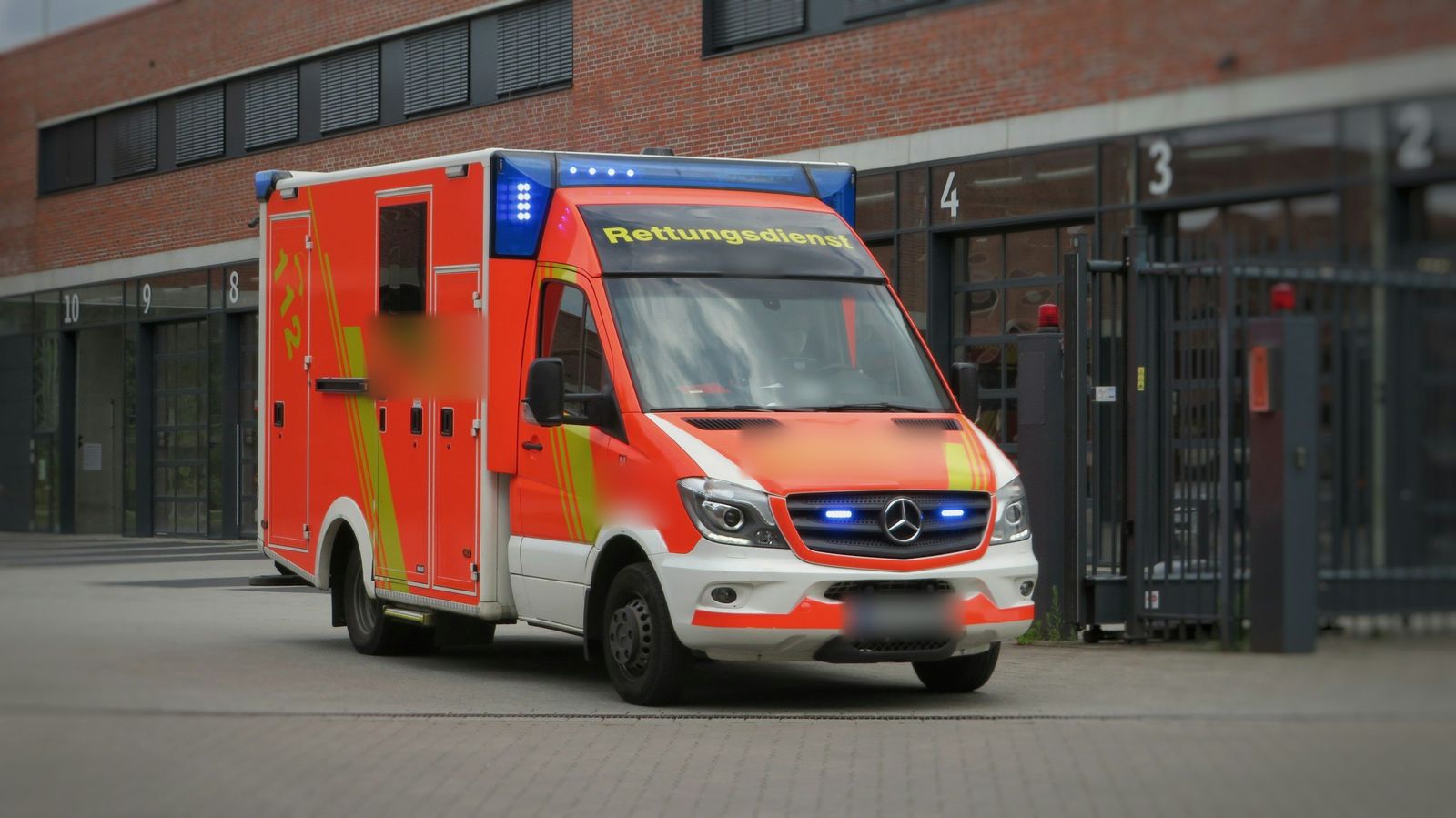 Rettungswagen mit Blaulicht fährt aus der Rettungswache aus